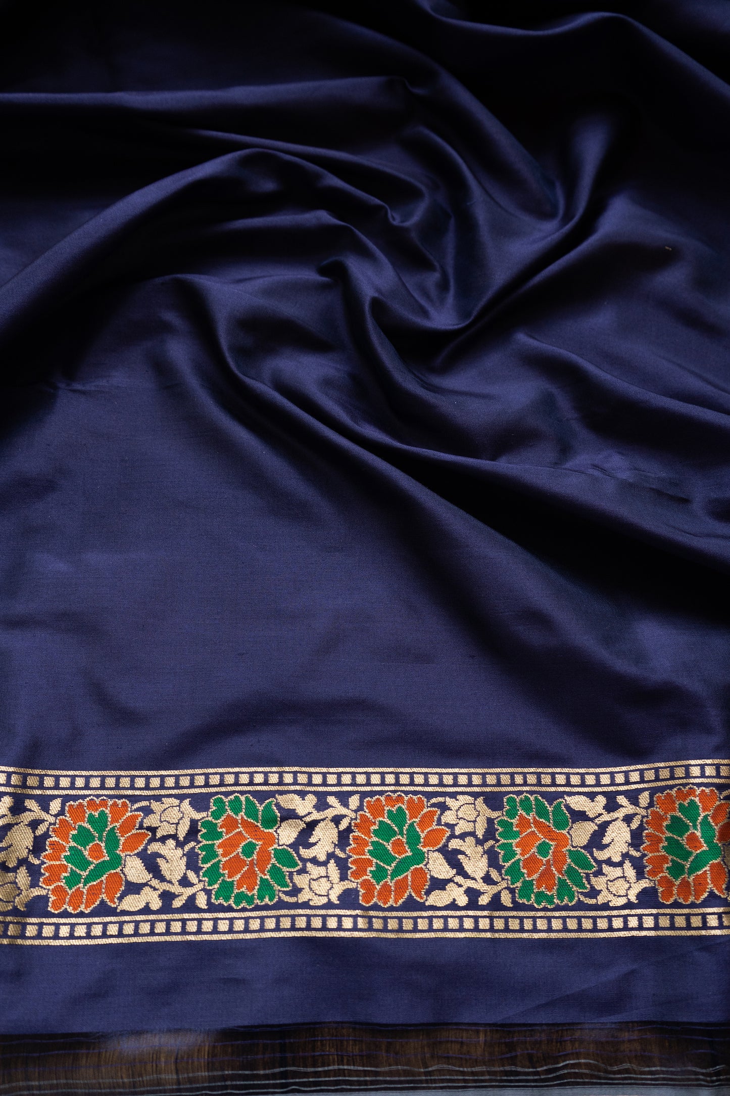 A graceful blue Banarasi saree with floral motifs and zari borders, styled with a striking pink blouse piece