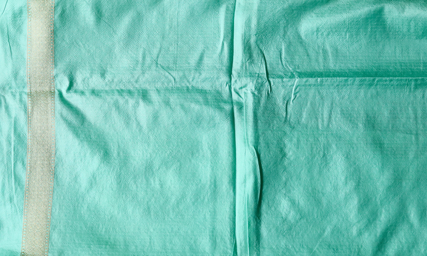 A woman graces a sky-blue Booti Katan Upada saree enriched with zari borders and a leheriya pallu, completed with a matching blouse piece — a stunning Banarasi saree look.