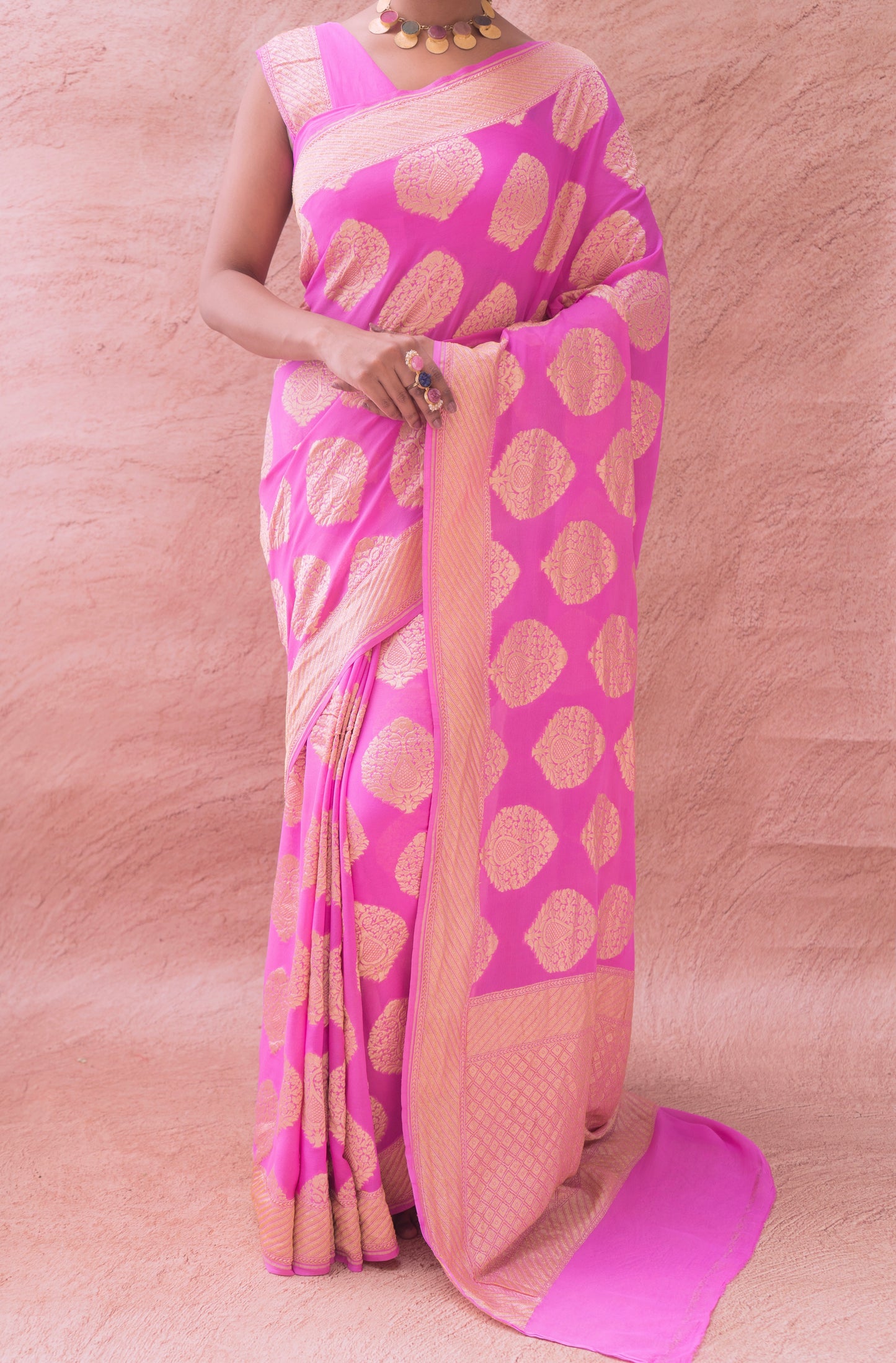 Timeless charm in a pink Banarasi saree with gold detailing, highlighted against a neutral background