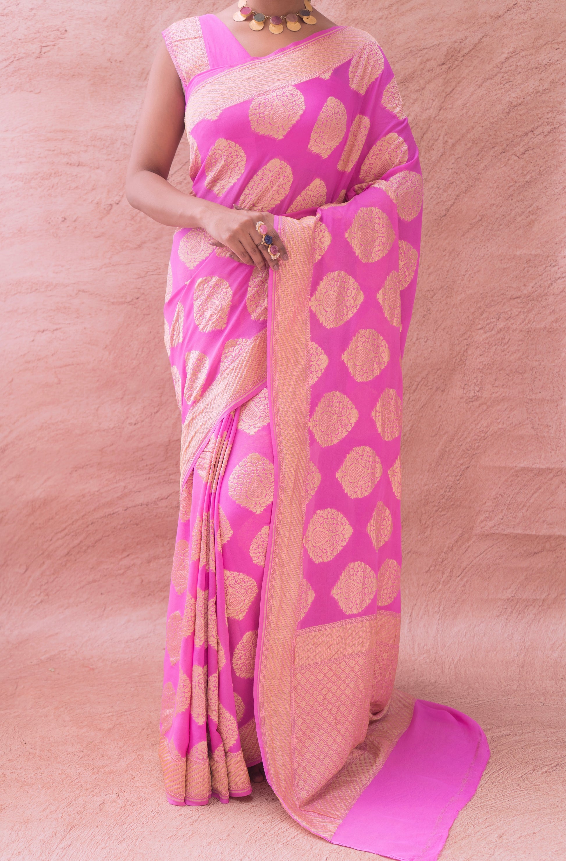 Timeless charm in a pink Banarasi saree with gold detailing, highlighted against a neutral background