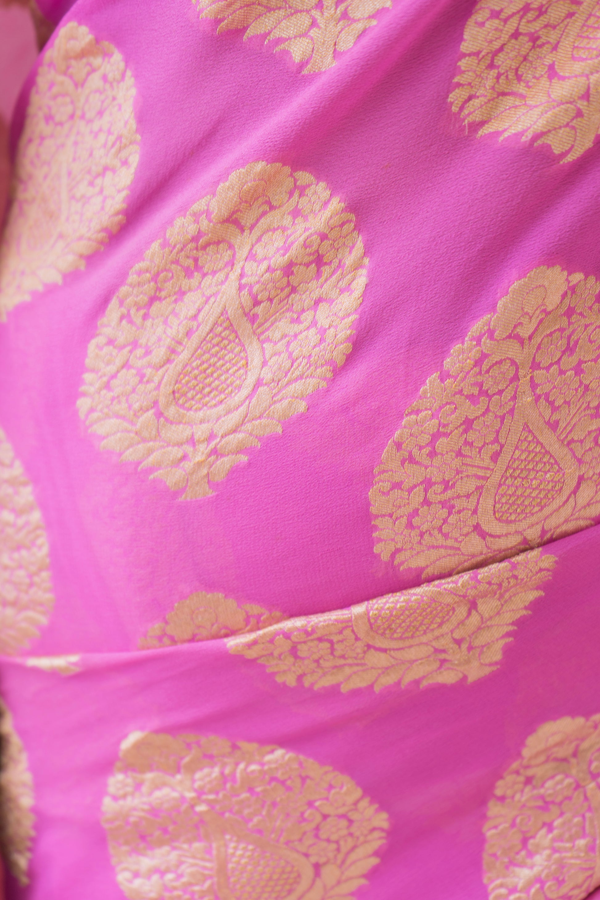 A beautiful pink Banarasi saree with gold motifs, worn gracefully against a soft neutral background