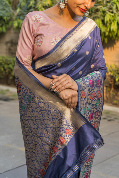 A beautiful blue Banarasi saree with floral patterns and golden zari borders, paired perfectly with a pink blouse piece 