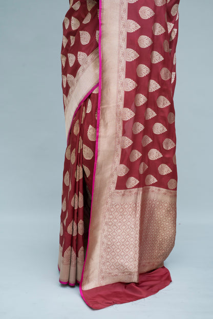 Experience timeless elegance with our maroon Banarasi saree in white patterns, captured against a serene grey backdrop.