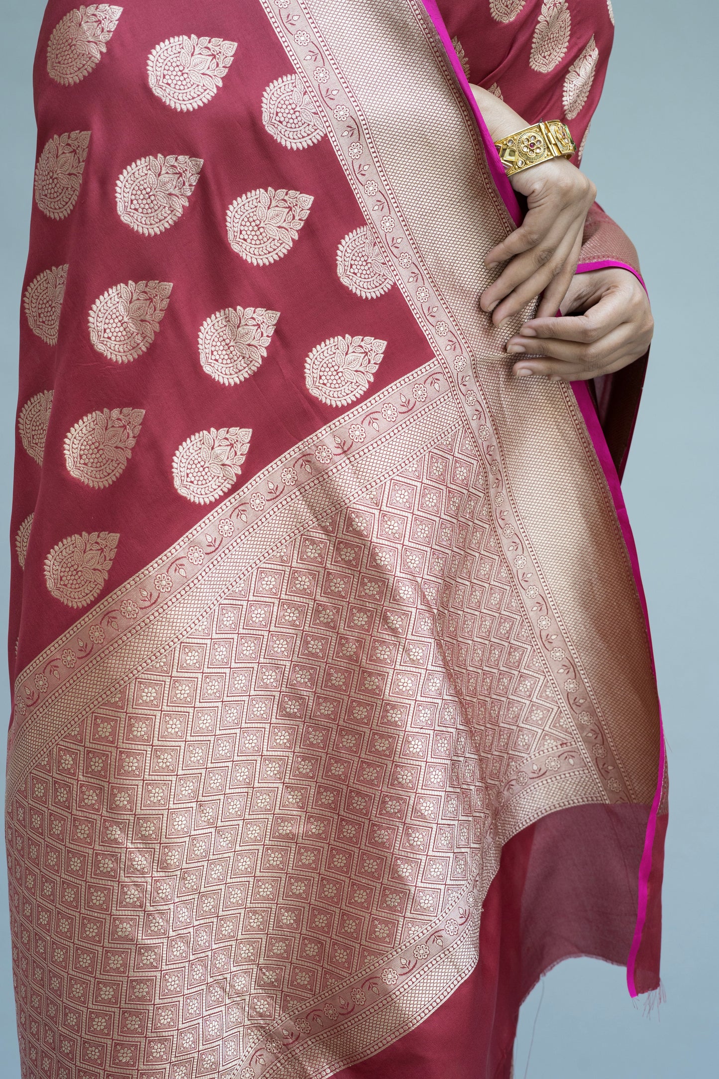 Maroon Banarasi beauty with white motifs—effortlessly stunning on a grey background.