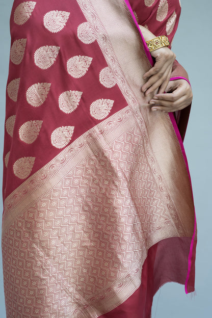 Maroon Banarasi beauty with white motifs—effortlessly stunning on a grey background.