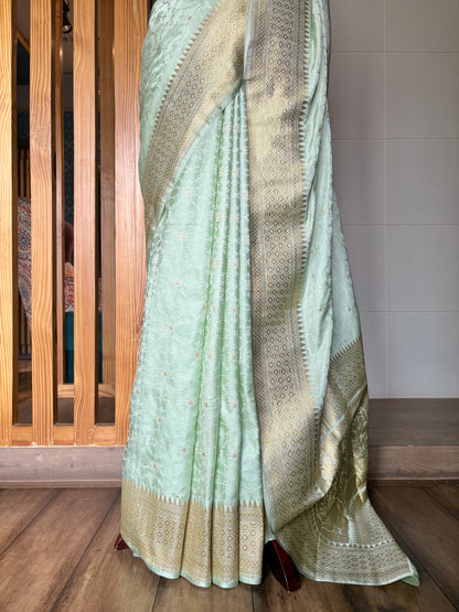 Elegance in focus: light green Banarasi saree with gold motifs on a mannequin over a subtle neutral backdrop