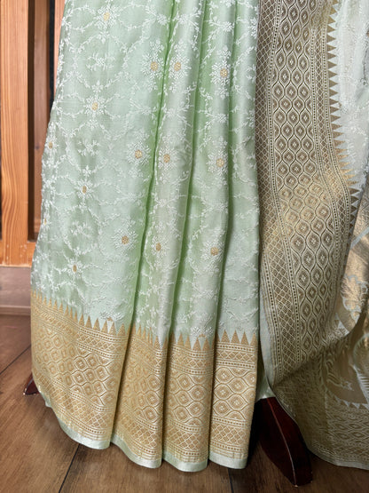 Pure sophistication: light green Banarasi saree with ornate gold motifs on a mannequin in a neutral setting.
