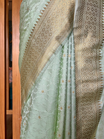 Light green Banarasi saree with rich gold patterns showcased on a mannequin against a calm neutral background.