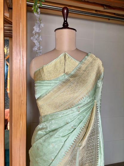 Timeless charm in a light green Banarasi saree with gold designs, highlighted on a mannequin against a neutral background.