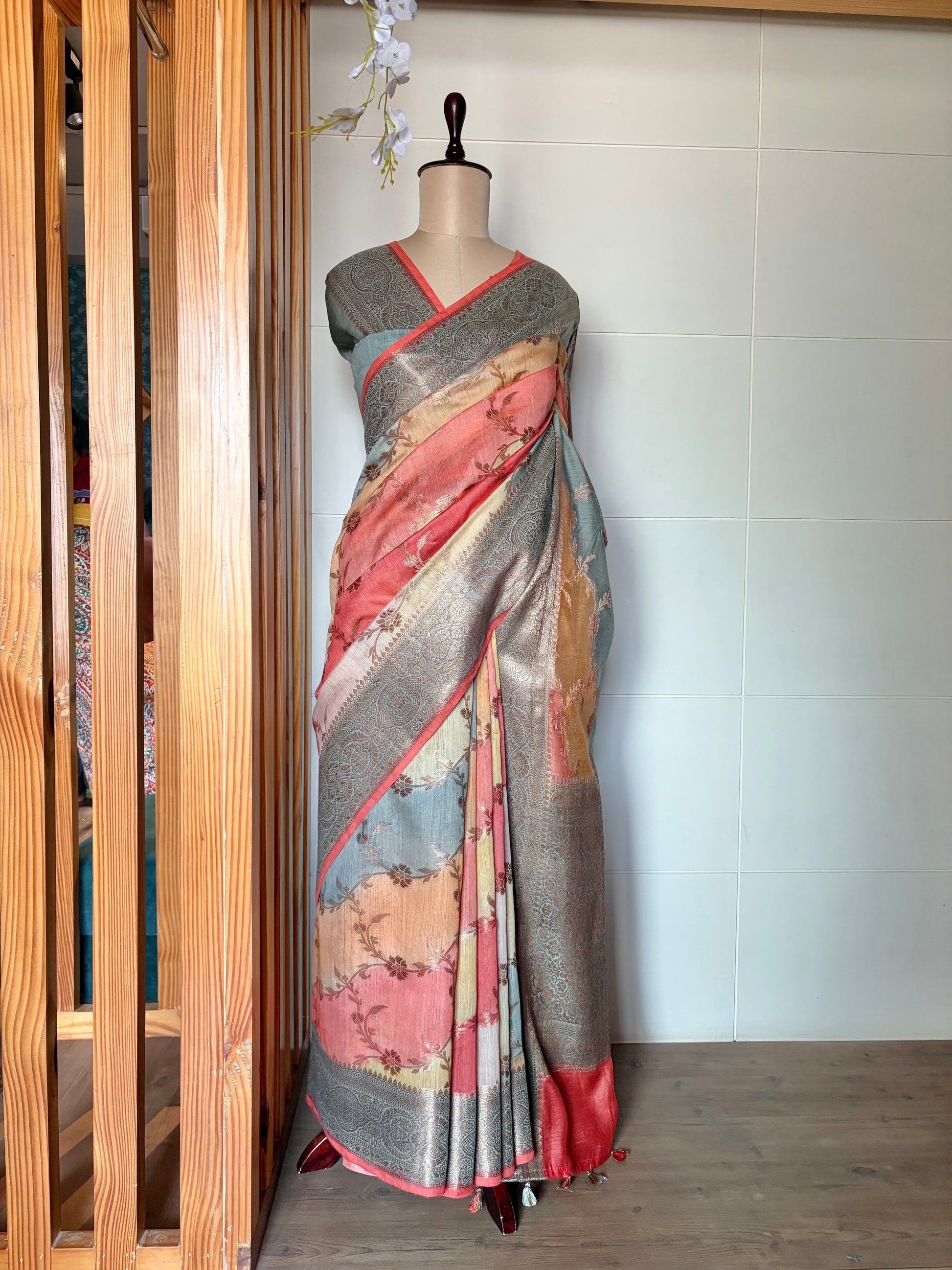 Luxury Banarasi saree with a floral pattern displayed on a mannequin against a white wall