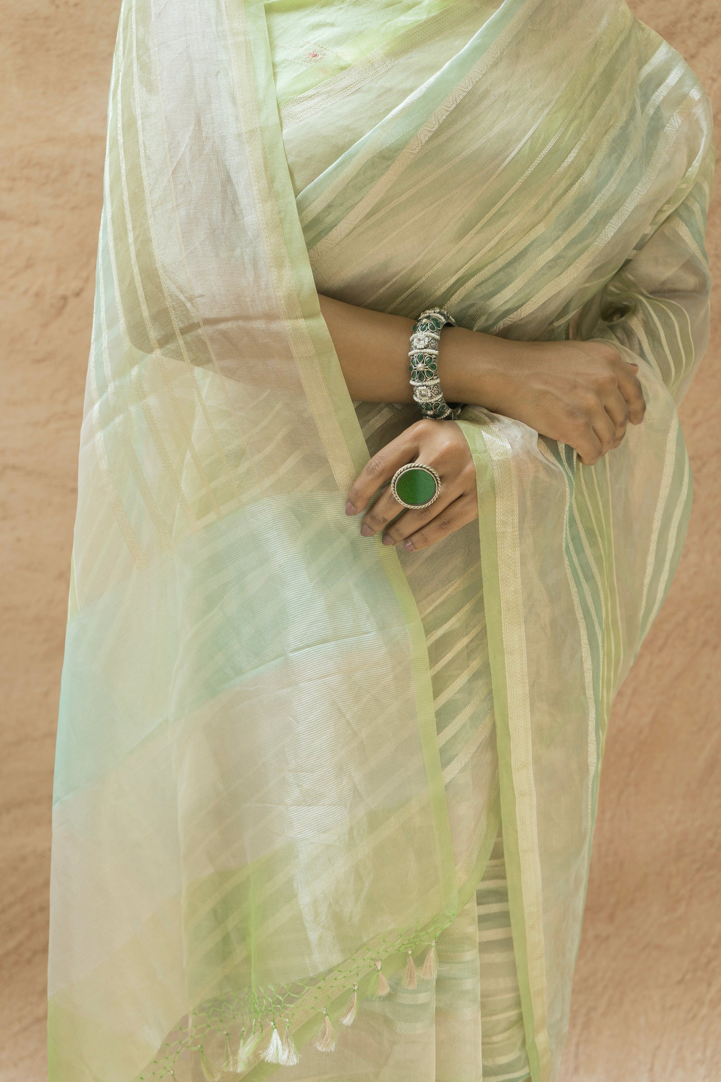 Elegant light green luxury Banarasi saree styled with minimal patterns and a soft beige background