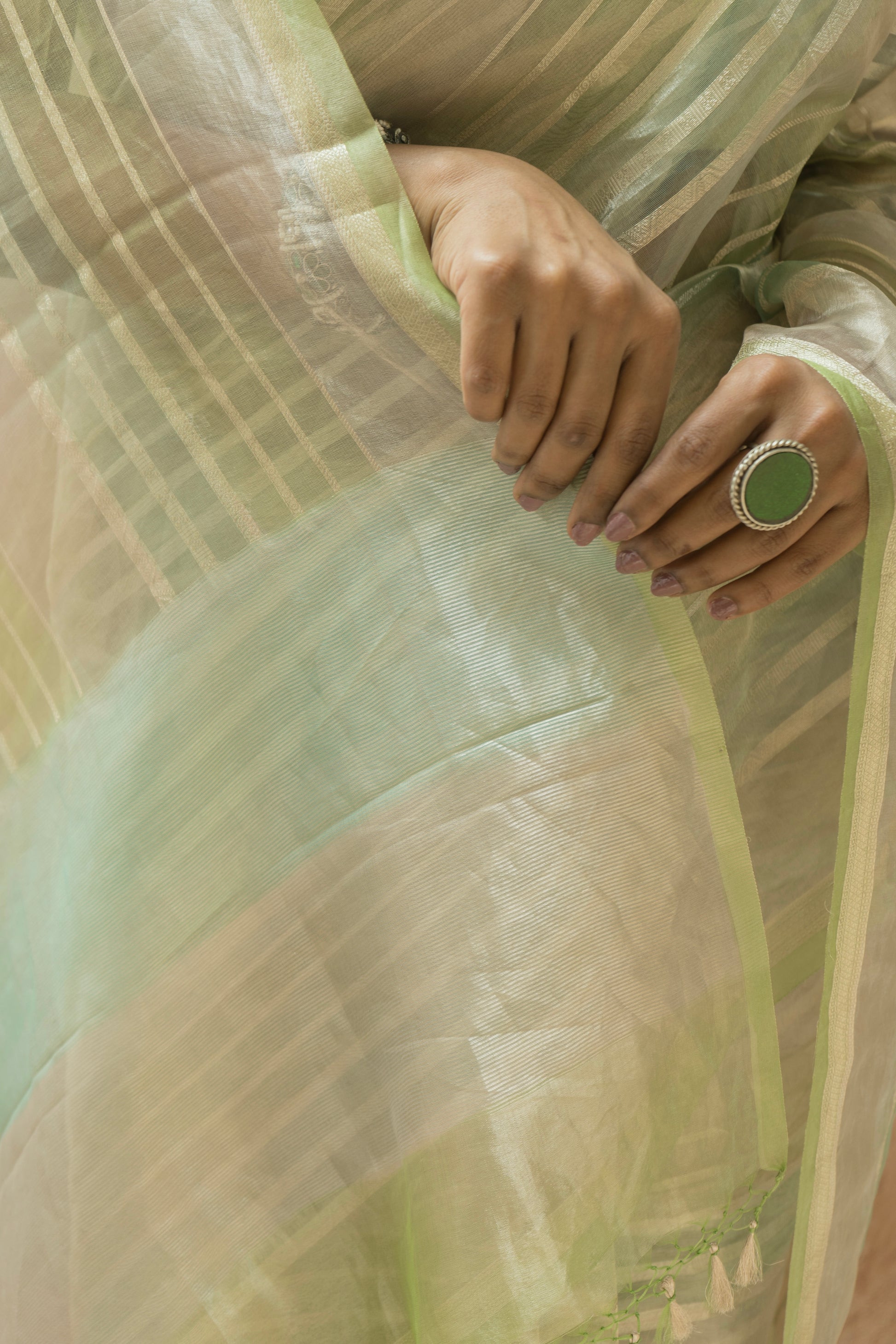 Light green luxury Banarasi saree with soft pattern detailing worn against a beige background