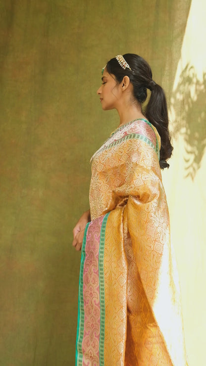 Elegance captured in a mustard yellow Banarasi saree featuring geometric motifs, floral accents, and a green-gold border.