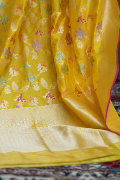 Timeless charm in a yellow Katan Multi-Meena Banarasi saree adorned with floral patterns and fine zari work, complete with a solid blouse piece.