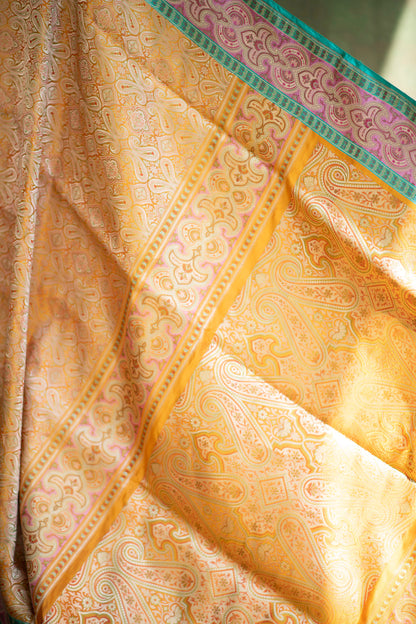 Mustard yellow Banarasi charm with geometric and floral detailing, framed by a bold green-gold border