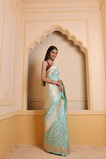 A woman adorns a sky-blue Booti Katan Upada saree featuring booti weaving, zari borders, and a leheriya pallu — a refined Banarasi saree statement.