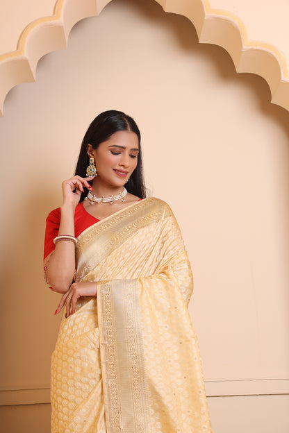 A woman draped in a light cream Banarasi saree adorned with intricate zari work for a timeless, regal look.